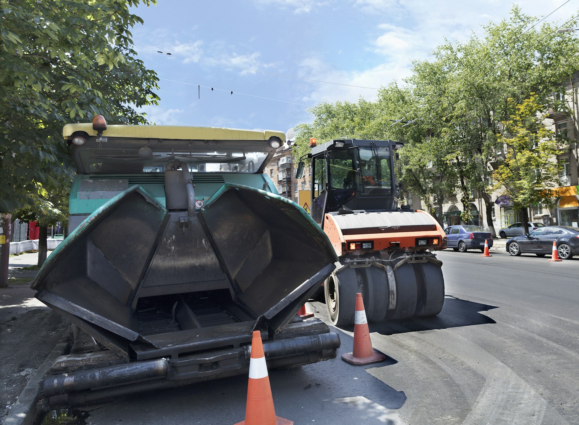 heavy asphalt paver and road vibrating roller seal ready for repair roads in a modern city